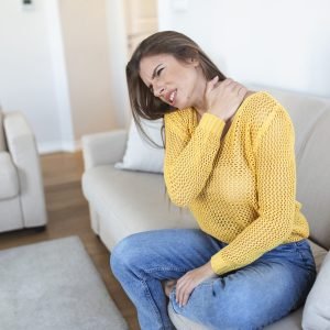 Woman suffering from backache at home. Lower Back Pain . Woman feels back pain massaging aching muscles, sad woman suffers from low-back